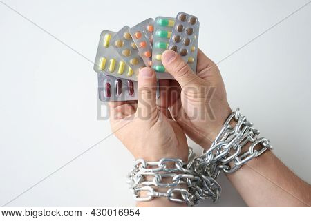 Male Hands Tied With Chain And Hold Various Medical Pills Closeup