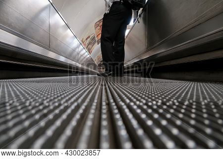 Low Angle View Of A Male Commuter Standing On Moving Walkway