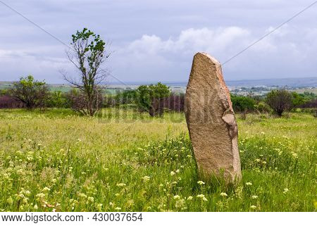 Old Sandstone Boundary Stone Among The Green Steppe On A Cloudy Summer Day