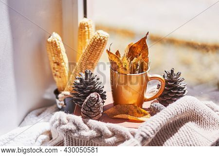 Corns, Autumn Leaves, Pine Cones And Coffee Cup On Windowsill. Creative Autumnal Background Near The