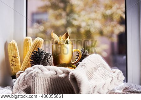 Corns, Autumn Leaves, Pine Cones And Coffee Cup On Windowsill. Creative Autumnal Background Near The