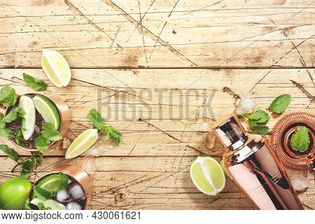 Moscow Mule Cocktails In Copper Mug With Lime, Ice, Ginger Beer, Vodka And Mint. Wooden Background, 
