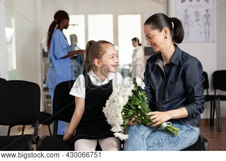 Family Bringing Flowers During Clinical Consultation Waiting In Hospital Hallway Area. Healthcare Su