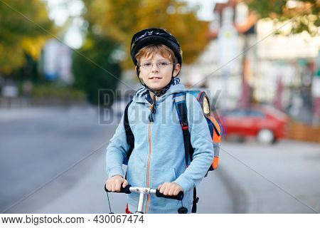 Active School Kid Boy In Safety Helmet Riding With His Scooter In The City With Backpack On Sunny Da