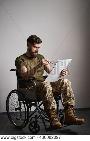 Young Military Man Sitting In A Wheelchair And Painting On A Canvas