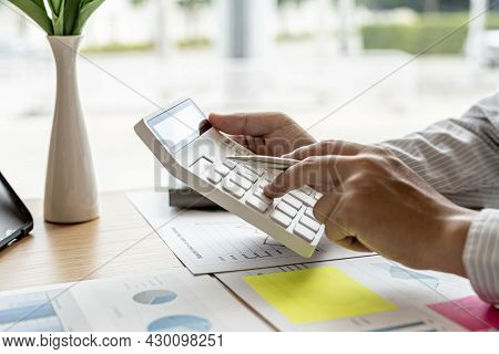 The Financial Officer Presses The White Calculator, He Calculates The Numerical Balance On The Docum
