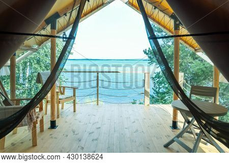 Part of glamping house interior with table and chairs and blue ocean on sunny day