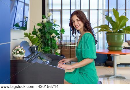 Young Caucasian Musician In Green Dress Playing A Piano In The Hotel Lobby.