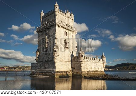 View Of The Famous Torre De Belem Near The Portuguese City Of Lisbon, With Blue Sky And White Clouds