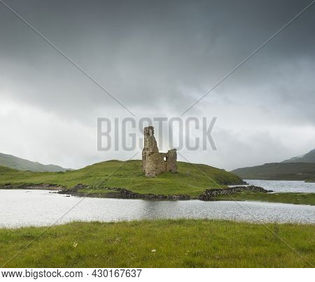 Landscape With Ancient Ruins Of The Small Castle Of Ardvreck In Scotland On A Lake And With Cloudy S
