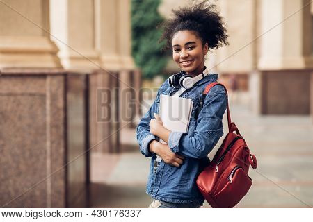Cheerful Black Student Girl Hugging Books Posing Near College Building