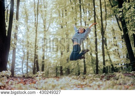 Cheerful Woman Full Of Joy Jumping In A Forest