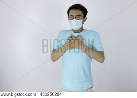 Young Asian Man With Heart Attack Or Cold Flu Feeling Breathless. He Wears A Surgical Mask And Also