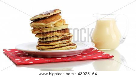 หวาน pancakes บนแผ่นกับนมข้นที่แยกต่างหากบนพื้นสีขาว