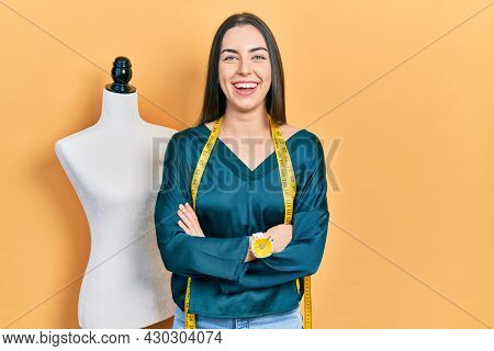 Beautiful woman with blue eyes standing by manikin with crossed arms smiling and laughing hard out loud because funny crazy joke. 