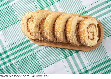 Rocambole, Sliced ​​rocambole Stuffed With Dulce De Leche On A Wooden Tray On A Table With Checkered