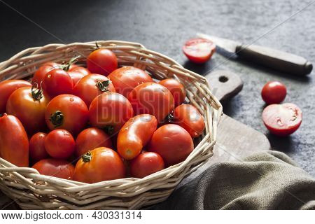Fresh Red Tomatoes In Whicker Basket On Black Background.