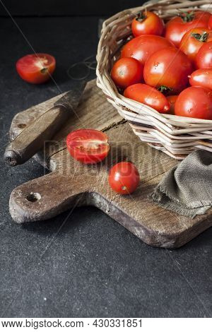 Fresh Red Tomatoes In Whicker Basket On Black Background. Copy Space