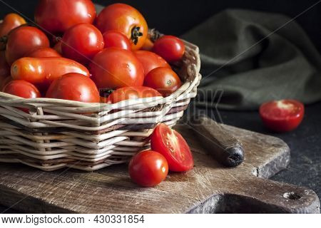 Fresh Red Tomatoes In Whicker Basket On Black Background.