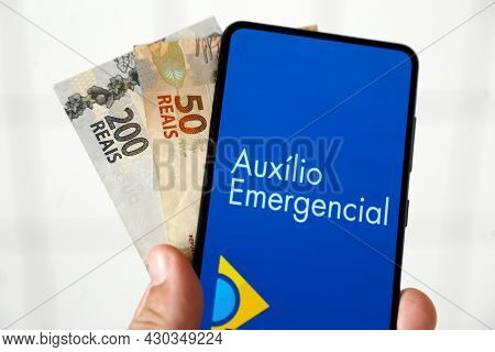 Minas Gerais, Brazil - April 6, 2021: Auxilio Emergencial In Mobile Phone Application And Money Bill