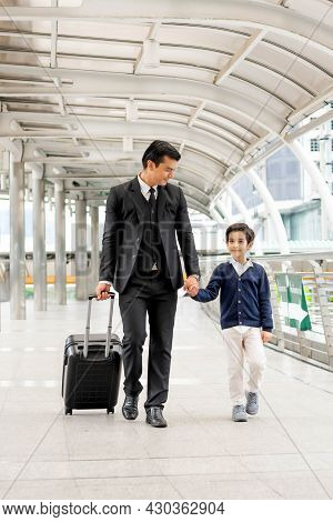 A Business Man Wearing A Suit With A Suitcase He Took His Lovely Son's Hand. And Walk Together Along