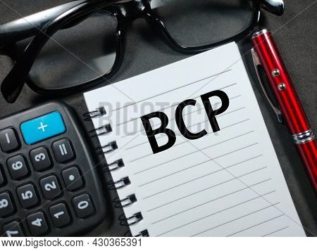 Text Bcp (business Continuity Plan) Writing On Brown Card With Pen,calculator And Glasses On Black B