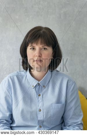 Portrait Of Middle-aged Woman With Dark Hair In Strict Blue Shirt. Young Seious Woman. Vertical Fram