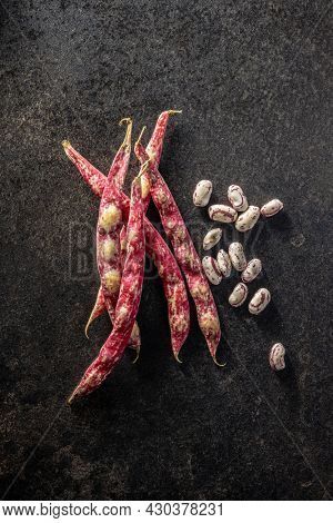 Cranberry beans. Borlotti beans. Beans pods on black table. Top view.