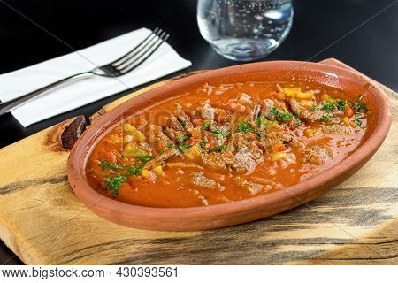 Meat Sauteed In White Casserole On Black Stone Table