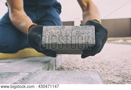 Worker lining paving slabs path