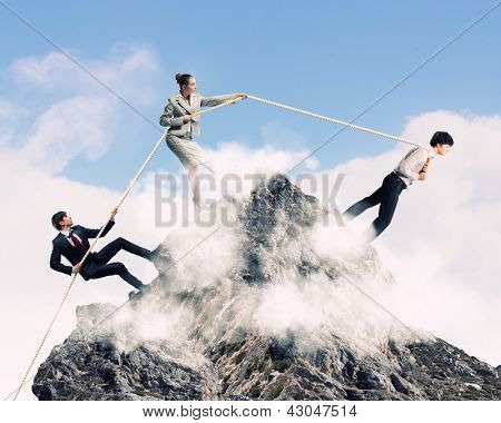 Imagem de três empresários puxando a corda no topo da montanha