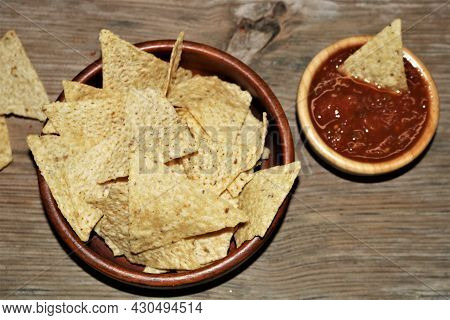 Tortilla Chips In A Bowl, With Picante Sauce, On A Wood Table Top.