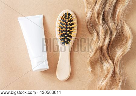 Lock Of Wavy Blonde Hair, Comb Brush And Tube Of Hair Care Product Top View