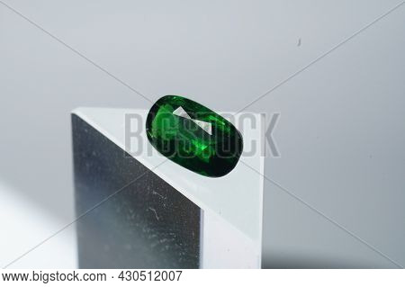 Natural Gemstone Green Tsavorite Garnet On A Stand On A Gray Background