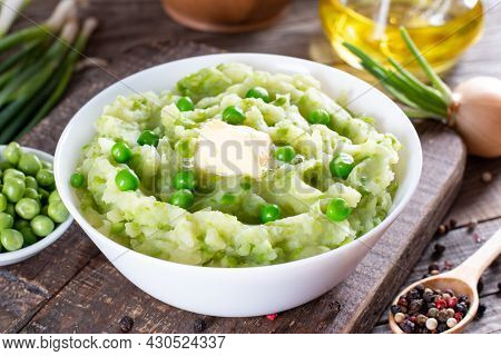 Delicate Mashed Potatoes With Green Peas, Flavored With Butter And Spices On A Wooden Table. Delicio