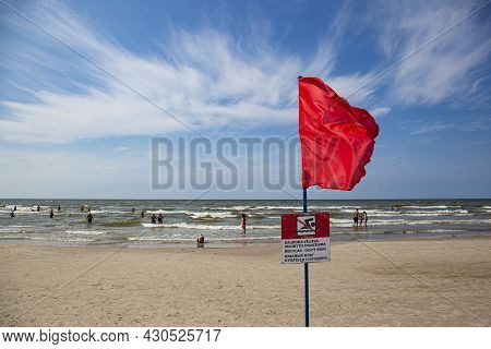 Naughty Vacationers On The Beach Swim In The Sea When Swimming Is Prohibited And A Red Flag Hangs