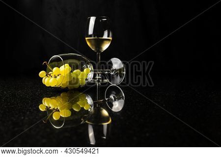 A Glass Of Wine And Glass With Grapes With Reflecton On Black Background