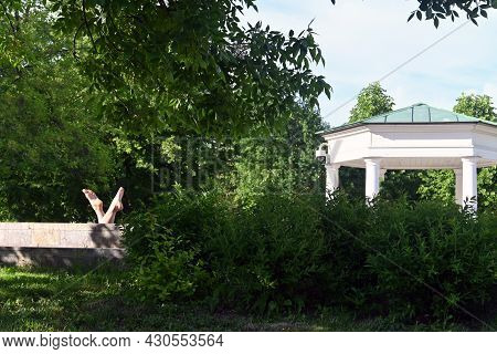 On A Summer Day, People Relax In The Garden. View Of The Trees, Pond, Bridge In The Yusupovsky Garde