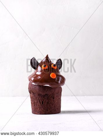 Chocolate Cupcake With Cute Face And Ears On The White Table. Halloween Dessert Reminding Dog Or Bat