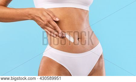 Closeup Of Young Woman Apply Lotion On Her Belly