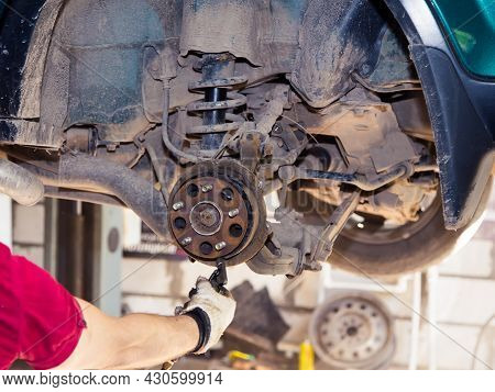 Hands Blow Off Dirt From The Worn Rear Wheel Hub With A Jet Of Air. In The Garage, A Person Changes 