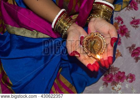 Hands Of An Indian Woman Holding Diya Or Pradip ( Oil Lamp ) On Diwali Festival. Selective Focus On 