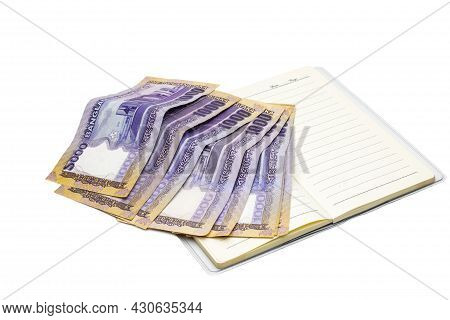 Scattered Thousand Taka Bangladeshi Banknotes Above A Diary On White Background