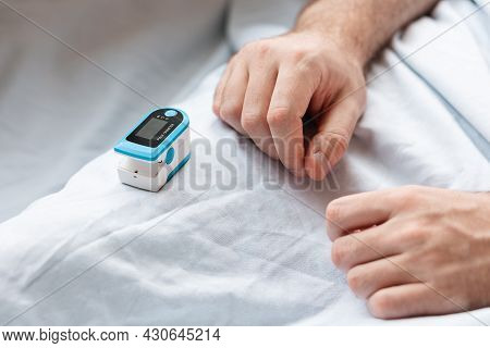 Close Up Of Hands Of Hospitalized Patient, Lying At Bed And Pulse Oximeter. Concept Of Determination