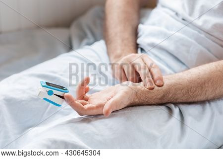 Patient Lying At Bed With Pulse Oximeter Adnd Try To Measure The Pulse With Hands. Close Up Of Hands