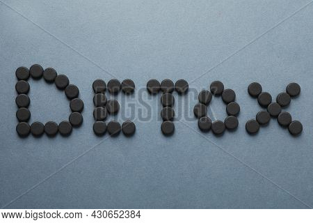 Word Detox Made Of Activated Charcoal Pills On Grey Background, Flat Lay. Potent Sorbent