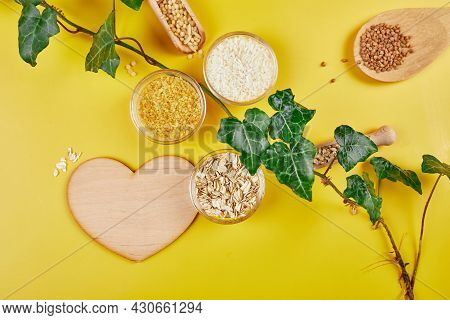 Flat Lay Of Set Of Heap Various Grains And Cereals With Greens Leaves On Yellow Background