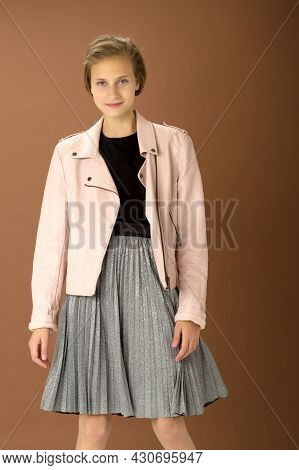 Happy Girl Whirling Against Brown Background. Joyful Attractive Brown Haired Teen Girl Dressed Pink 