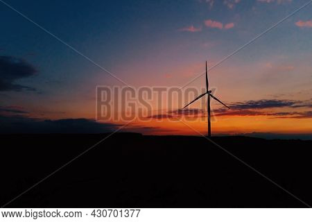 Windmill Silhouette At Sunset Sky. Wind Turbine Generator. Wind Energy Concept. Suistanable And Rene