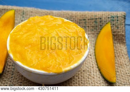 Closeup Of Ripe Mango Pulp In Bowl On Burlap Fabric